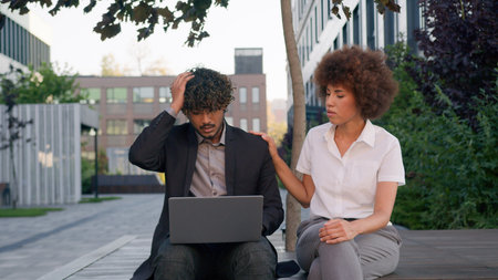 Business diverse multiracial partners in city outdoor company office sad upset Indian man Arabian businessman talk failure lost problem with laptop African American woman businesswoman support calmingの写真素材