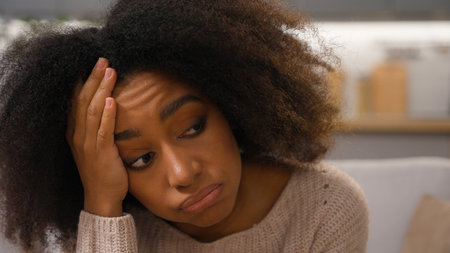 Close up sad despair girl with stress depress lying on couch young African American anxious woman rest on sofa millennial lady suffering from negative thoughts unwanted pregnancy relationship problemsの写真素材