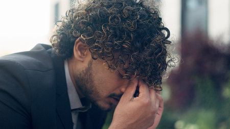 Close up worried Indian businessman stressful business employer man entrepreneur Hispanic manager talking mobile phone answer call bad news hearing listening problem headache stress in cityの写真素材