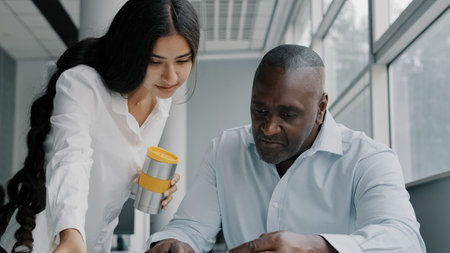 Two colleagues business partners office co-workers analyze paperwork check information. Arabian...