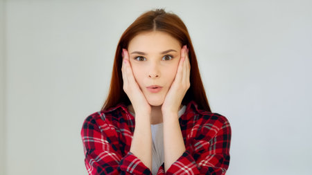 Surprised ginger girl student teenager feel good shock admiration female face excited winner says wow positive reaction holds head by hands successful result millennial young woman win lottery prizeの写真素材