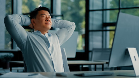 Asian korean senior businessman employee relaxing alone lean on office chair put hands behind head comfort rest feels satisfaction by computer work done take break after success deal working day offの写真素材