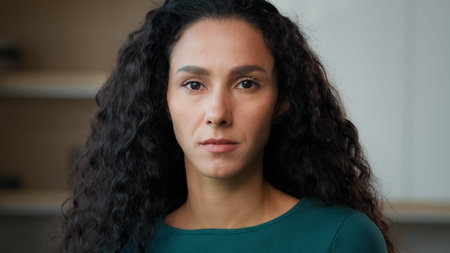 Sad depressed woman upset stand alone in kitchen looking at camera with resentful offended facial...