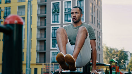 Powerful latina sportsman gymnast muscular african american healthy man lifting legs on bars city...