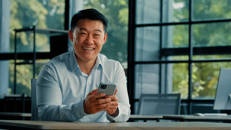 Surprised Asian successful businessman emotional man professional winner receive good message on...
