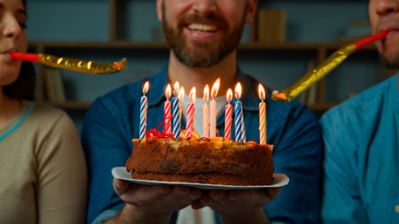 Cropped view caucasian adult happy bearded man celebrate birthday at home diverse african caucasian friends congratulate male with festive cake blowing party whistles make surprise annual traditionの写真素材