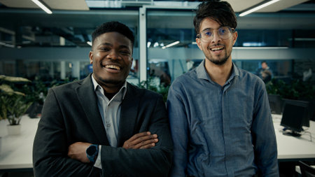 Multiracial business colleagues smiling diverse men arabian and african businessmen co-workers employees stand in office together posing arms crossed portrait successful male people corporate teamworkの写真素材