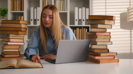 Caucasian student happy smiling girl woman studying with laptop and books homework learning online knowledge prepare for test exam study at library cram SAT test bookworm research history prep courseの写真素材