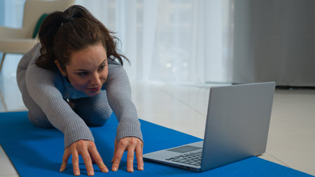 Female workout woman in sportswear stretching body watching fitness video tutorial laptop online...