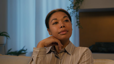 Pensive dreaming African American ethnic woman think thoughts at evening home thoughtful face female girl homeowner resting in night living room thinking future dream relaxing pondering look to sideの写真素材