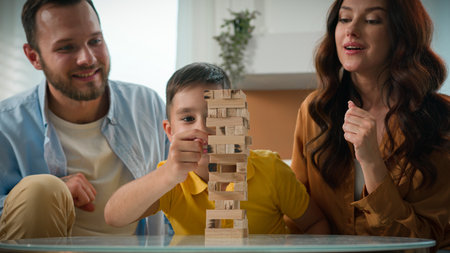 Happy cheerful Caucasian family spending time together at home mother father son man woman child kid boy playing board game in living room couch enjoying intellectual logical games play tower puzzleの写真素材