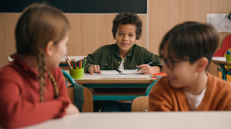 Multiracial diverse noisy little classmates multiethnic students pupils people children diversity kids friends noisy talking in school class at lesson sitting at table education learning studying talkの写真素材