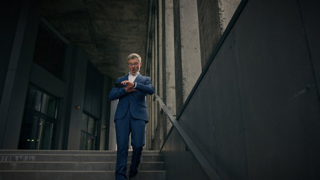 Caucasian mature old man businessman senior business employer walking outdoors on stairs near office...