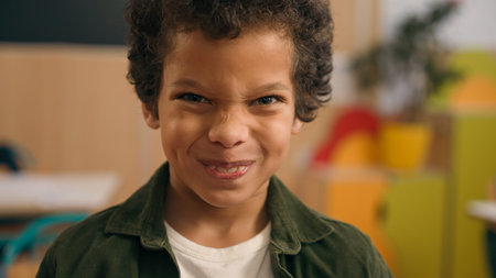 Portrait little African American boy looking at camera primary school adorable biracial guy kid schoolboy son child baby pupil student in kindergarten studying education smile laughing grimacing faceの写真素材