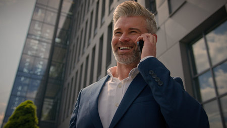 Happy smiling city building developer talk cellphone speaking calling joyful middle-aged senior...