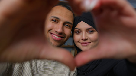 Newlyweds diverse ethnic married couple african american man with beloved arabian woman looking at camera through heart frame united husband wife hands in love shape Valentines Day romantic relationの写真素材