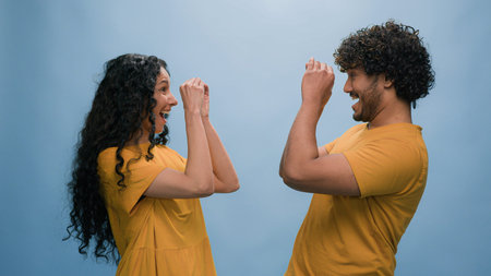 Portrait in blue background studio funny couple Indian man Arabian woman Hispanic friends girl guy...