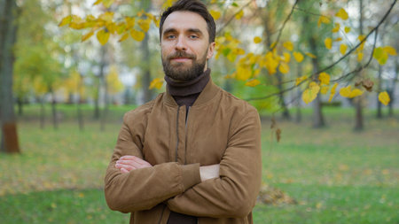 Portrait in autumn park outdoors city nature confident friendly happy Caucasian millennial 30s man guy father male posing looking at camera hands crossed confidence holiday healthcare crossing armsの写真素材