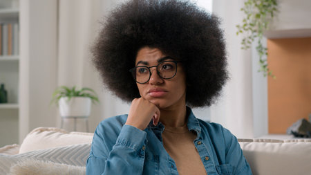 Close up sad pensive boring female portrait at home ethnic upset dissatisfied puzzled confused girl alone thoughtful stress anxiety worried African American woman thinking suffering solving problemの写真素材