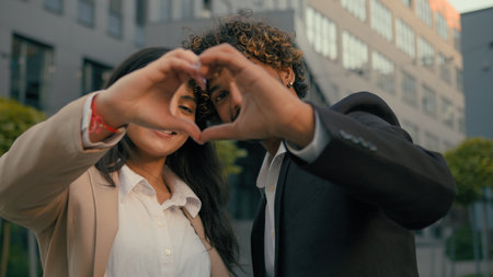 Indian couple Arabian business man businessman woman businesswoman corporate colleagues coworkers partners showing heart shape with hands fingers at camera in city near office building love supportの写真素材