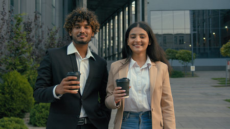 Indian Arabian business partners people coworkers colleagues businessman man businesswoman woman workers managers with take away coffee tea cups posing smiling looking at camera smile in city downtownの写真素材