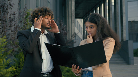 Two business people in city Arabian woman businesswoman manager intern holding folder papers documents bad result mistake stressed angry Indian businessman screaming shouting yellingの写真素材