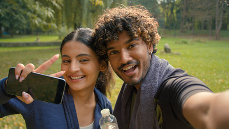 couple girl guy man woman friends sport workout fitness exercise fit make selfie photo with phone smiling posing video call streaming bloggers vloggers influencers in park outdoorsの写真素材