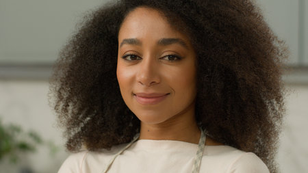 Portrait African American woman ethnic girl biracial female chef cooker baker mother housewife homeowner wife smiling posing in home modern kitchen interior wearing apron cooking food delivery cookの写真素材