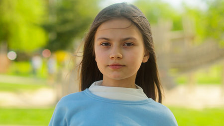 Caucasian adorable cute little girl child adopted daughter schoolgirl outdoors in city serious calm sad innocence face offended kid looking camera family custody childcareの写真素材