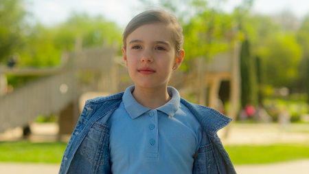 Happy little girl Caucasian child daughter female kid schoolgirl student pupil friendly hello gesture greet waving hand children playground family park outdoors city school education childhoodの写真素材