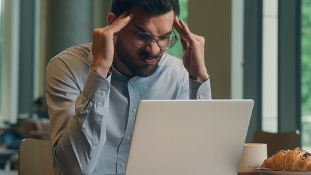 Indian male guy businessman Arabian man tired exhausted business worker freelancer online work laptop in cafe stress health headache sad upset displeased angry mistake computer breakdown fail troubleの写真素材