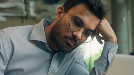 Sleepy tired bored overworked businessman Arabian Indian male business man exhausted guy upset sad...