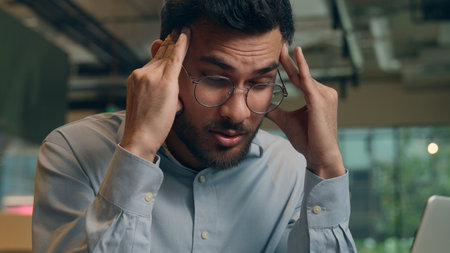 Businessman upset paperwork problem Indian Arabian business man visitor in cafe male sad frustrated anxious guy freelancer laptop work tired stress overwork pain head headache trouble health migraineの写真素材