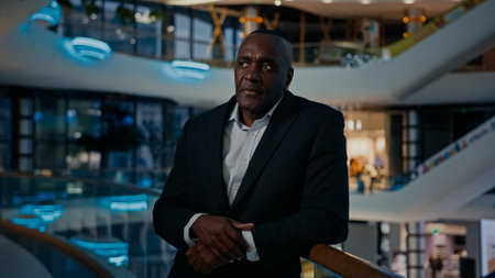 Middle-aged African entrepreneur ethnic man worker businessman indoors answer call listening good news by mobile phone calling talk victory achievement winning smartphone talking happy business offerの写真素材