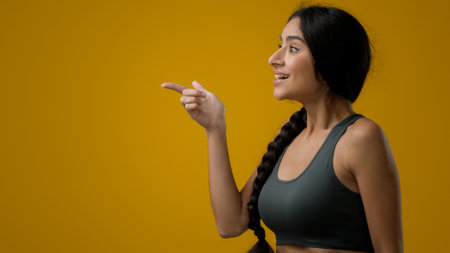 Wonder surprised amazed Indian woman girl female in studio yellow background pointing to side to empty copy space advertisement amazement amazing looking to aside astonishment disbelief excited shockの写真素材