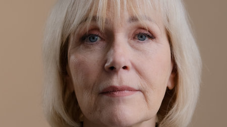 Close up female portrait in studio indoor head face wrinkled calm serious granny mature 60s woman...