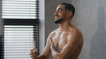 Muscular Arabian naked male Indian model sportsman guy 30s handsome relaxing bare wet man washing in...
