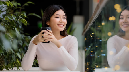 Asian girl woman smiling enjoying drinking fragrant delicious coffee hot tea morning cappuccino in...