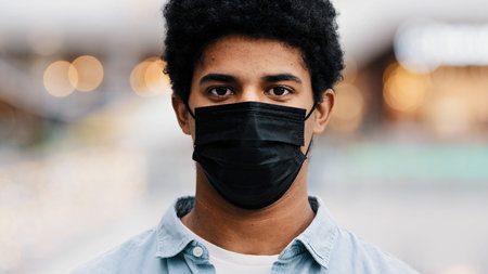 Portrait male masked face african american guy man taking off medical mask smiling looking at camera relief end of coronavirus finish pandemic recovery from covid disease victory virus free breathingの写真素材