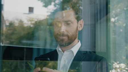 Close up reflection in glassy window blue glass Caucasian bearded 40s middle-aged man adult...