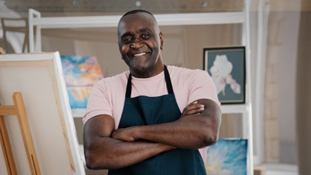 Portrait close up male happy old 50s painter art teacher African American happy elder senior middle-aged man artist talented designer creator posing crossing arms art studio finishing drawing picturesの写真素材