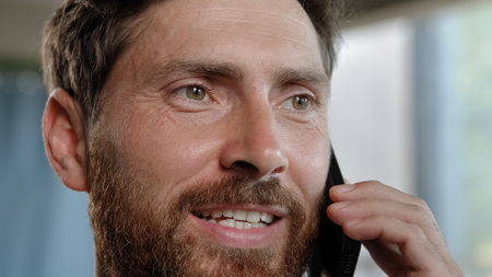 Close up portrait smiling 40s happy adult professional cheerful businessman with toothy smile business call talking phone in office agree say Caucasian bearded man salesman mobile conversation indoorsの写真素材