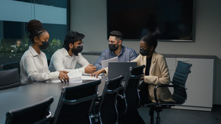 Multiethnic diverse business team partners office workers African American Indian Arabian colleagues in medical masks working together discuss startup project analyzing financial documents paperworkの写真素材