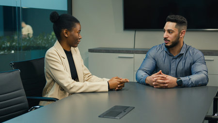 Indian Arabian man CEO businessman recruiter employer talking in office with African American woman...