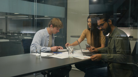 Group of coworkers woman men colleagues managers diverse businesswoman businessmen sit at table office boardroom team work with devices analyzing corporate business project graphs documents in companyの写真素材