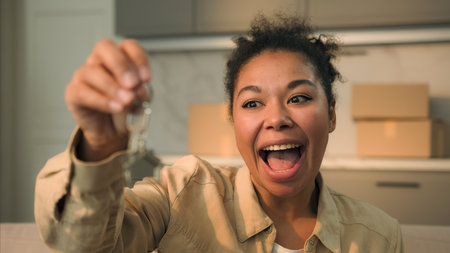 Happy African American woman joyful girl female buyer tenant laugh holding keys of new home buying own house buy rent apartment smiling homeowner real estate insurance loan mortgage credit moving dayの写真素材