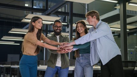 Happy business women men multiracial friends students group corporate colleagues stacking hands in...