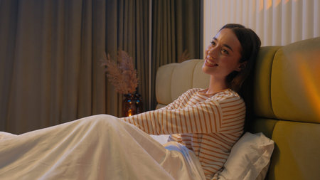 Happy Caucasian woman sitting on bed home comfortable cozy rest girl female bedroom smile pleasure...