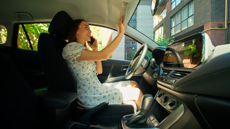 Smiling happy glad Caucasian positive car owner woman buyer female girl driver sitting inside automobile talking mobile phone call discuss buying new auto looking salon interior excited rental serviceの写真素材