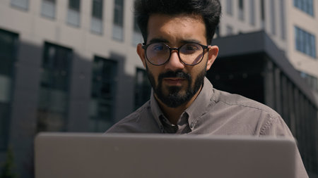 Indian Arabian adult man business employer working with laptop online networking remote freelance...
